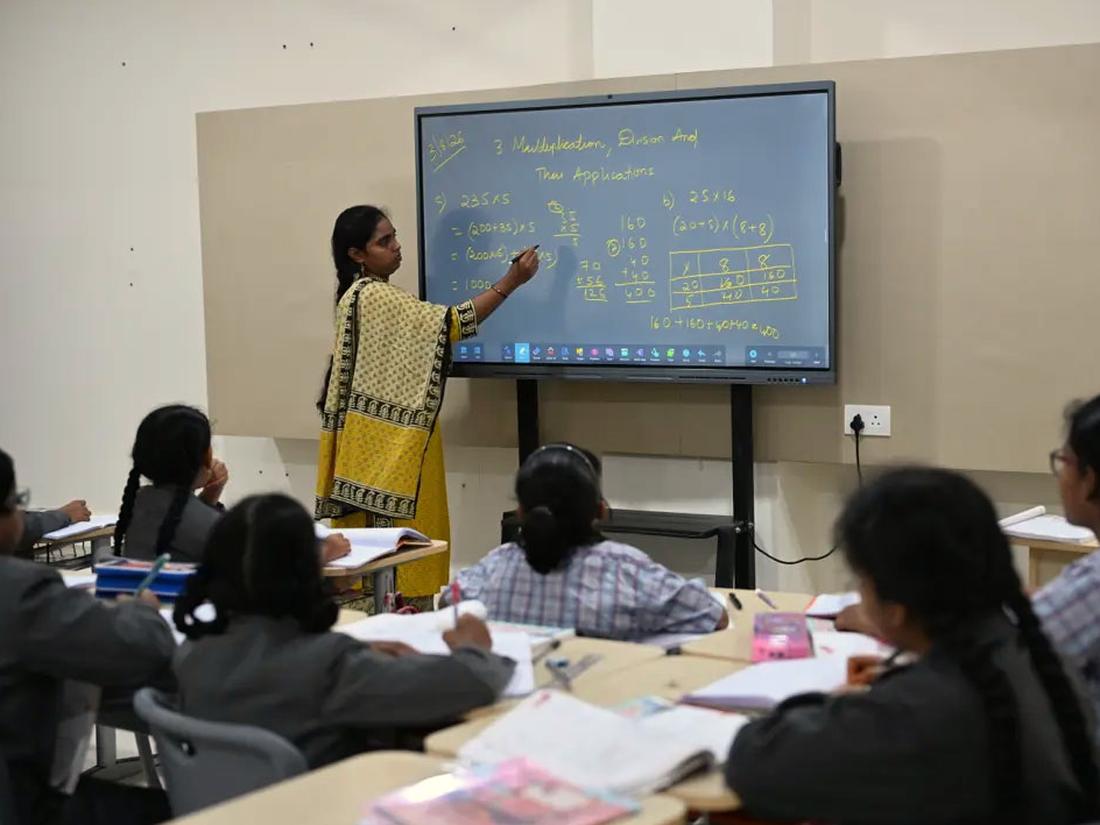 Teacher using an interactive panel to explain a concept to a class