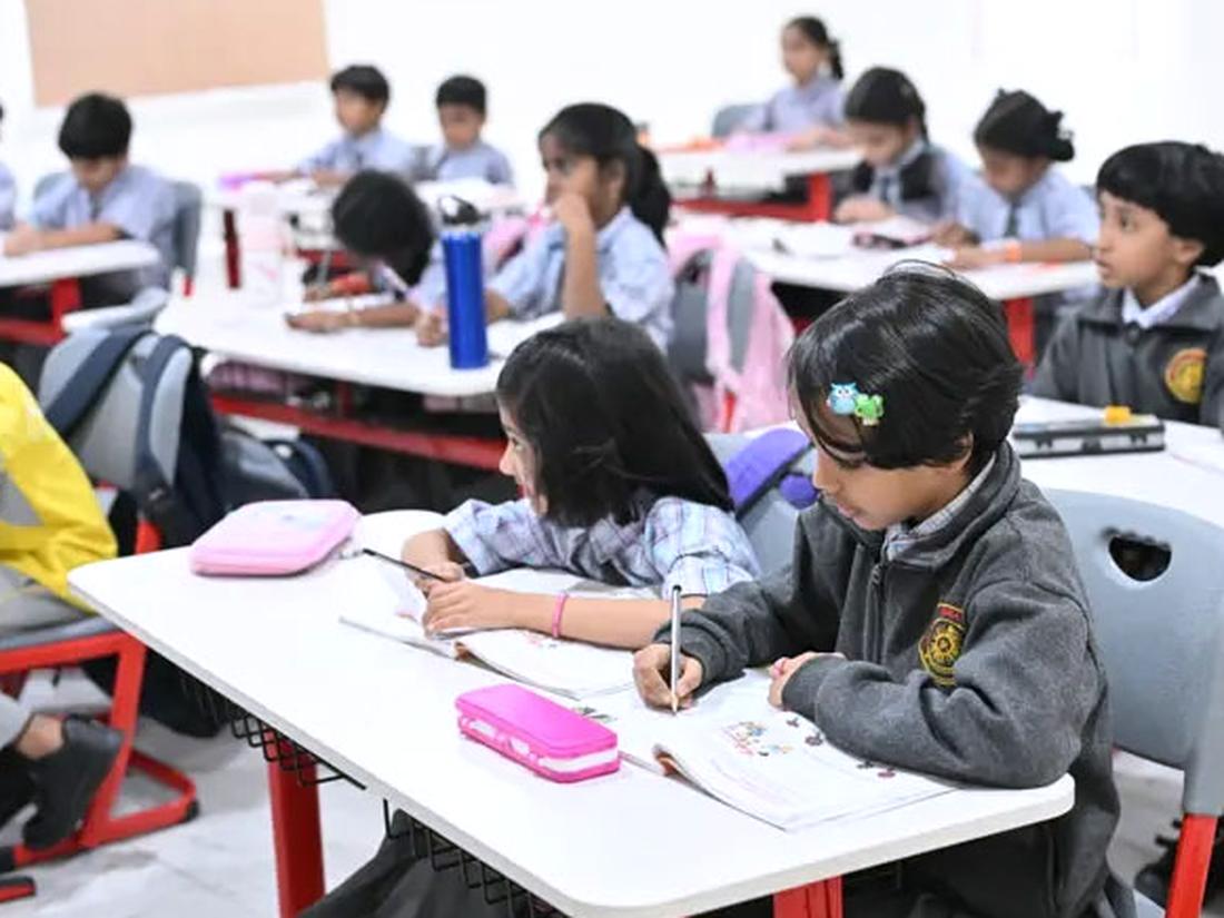 Primary students writing in notebooks at their classroom desks