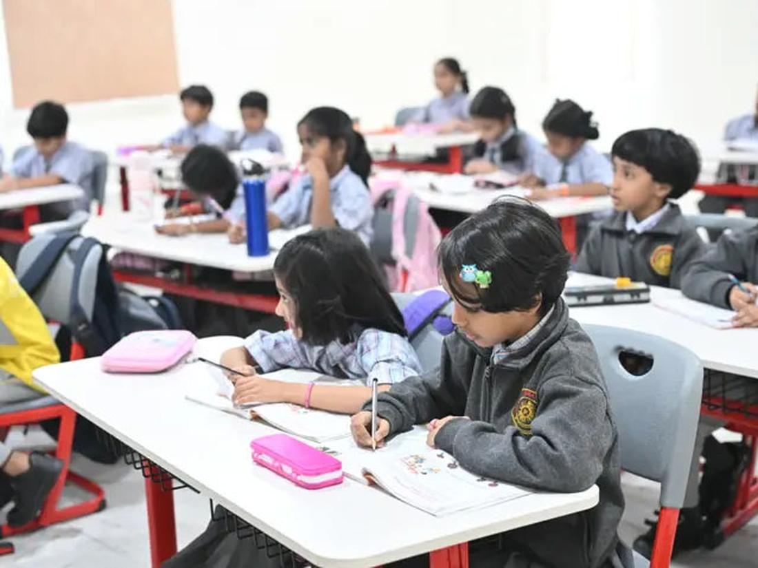 Primary students writing in notebooks at their desks Primary students writing in notebooks at their desks